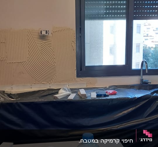 קיר עם טיח מוכן להדבקת אריחים, כלים על השיש